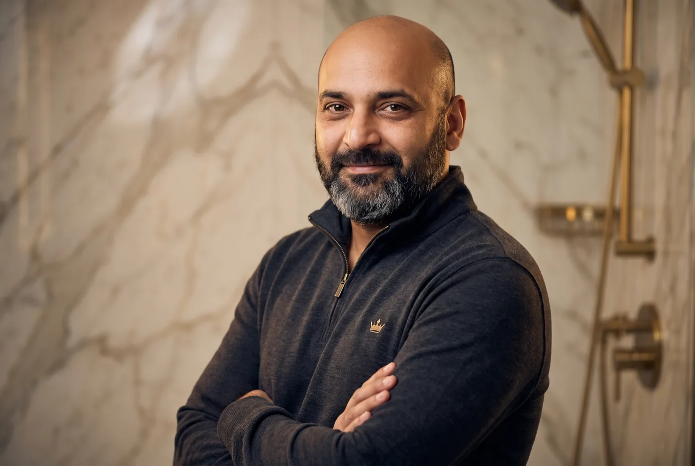 Shesare Monclus, owner of ROC Services, standing in a finished marble-and-brass bathroom